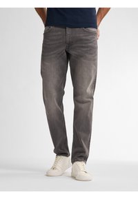 Vaqueros grises de denim con un ajuste relajado, con un sutil desgaste y diseño de cinco bolsillos, combinados con zapatillas blancas.