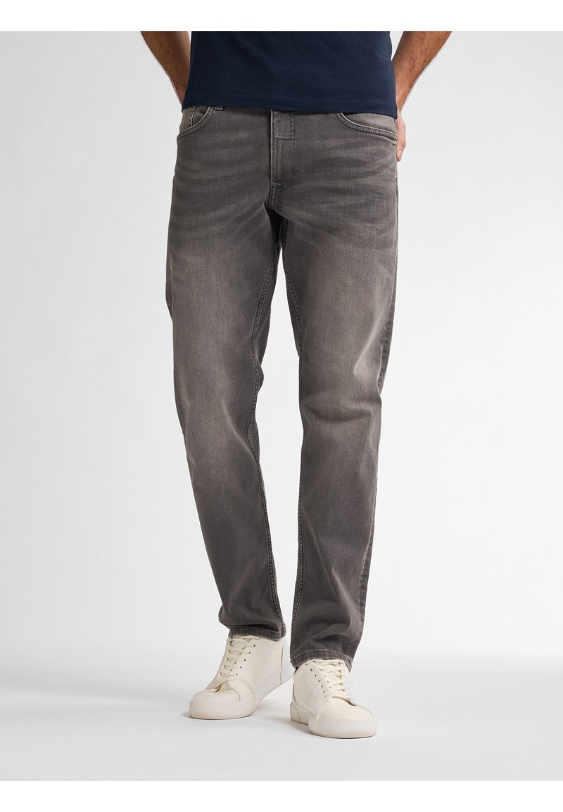 Vaqueros grises de denim con un ajuste relajado, con un sutil desgaste y diseño de cinco bolsillos, combinados con zapatillas blancas.