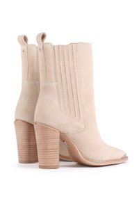 Bottines en suède beige à bout rond, avec des détails côtelés sur tige et un talon en bois empilé. Accent en argent sur le bout et anneaux de traction.