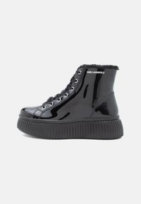 Botas de tornozelo em couro verniz preto com sola plataforma texturizada, forro de pelúcia e ilhoses metálicos. Marca na lateral.