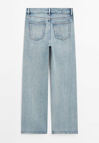 Vaaleansiniset farkut, joissa on leveä lahje, kaksi takataskua ja suora leikkaus helmassa. Liukas pinta, klassinen ompelu.