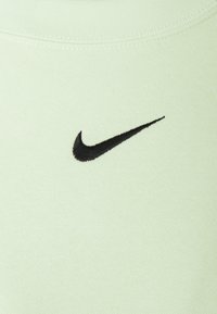 Světle zelená bavlněná látka s černě vyšitým logem Nike Swoosh, se hladkým povrchem a žebrovaným límečkem.