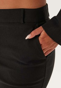 Svart skräddarsydd kjol med en slät textur, sidokrage och en figursydd midjeband som framhäver en elegant silhuett.