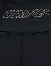 Svart sporttopp med logotypen "HUMMEL" i fet grå text. Har ett slätt material, en kroppsnära design och subtila sömnadsdetaljer.