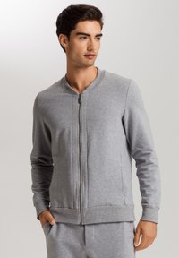 Felpa grigia con zip, collo tondo, maniche lunghe e polsini e orlo a coste. Texture liscia, con tasche laterali.