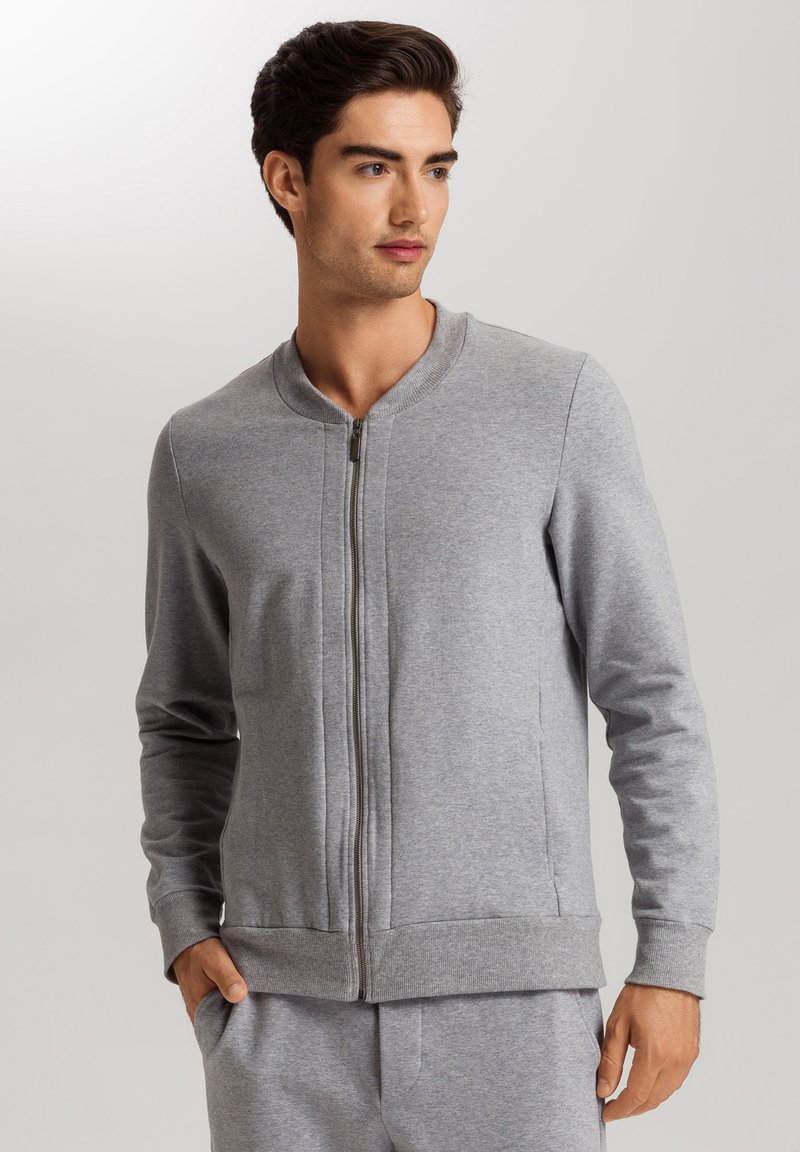 Felpa grigia con zip, collo tondo, maniche lunghe e polsini e orlo a coste. Texture liscia, con tasche laterali.