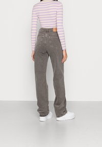 Gray high-waisted jeans with a relaxed fit, featuring back pockets and a textured cotton blend. Paired with a striped long-sleeve top.