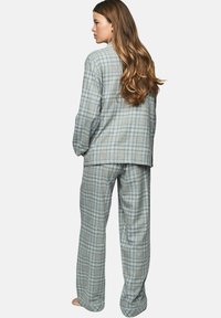 Ensemble de pyjama à carreaux gris comprenant une chemise à boutons et un pantalon assorti. Tissu doux avec des accents bleu clair et une coupe décontractée.