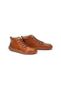 Zapatos altos de piel marrón con punta redonda, diseño con cordones y paneles laterales texturizados. Cuentan con una suela de goma con detalles de costura.