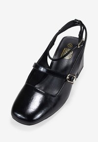 Chaussure à talon compensé en cuir noir avec un bout fermé, une bride de cheville et un fermoir. Texture lisse, design minimaliste et forme carrée. Taille 36.