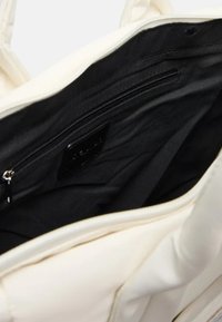Borsa tote bianca con interno nero, tasca con zip, texture liscia e manici robusti. La fodera è in tessuto morbido.