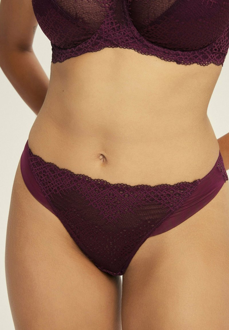 Burgunderfarbene Spitze und Netzunterwäsche mit einer gewellten Kante und kontrastierendem, einfarbigem Rücken, der mit komplizierten geometrischen Mustern verziert ist.