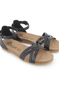 Sandalias de cuero negro con correas entrelazadas, hebillas en el tobillo y una plantilla de corcho. Suela plana con un acabado texturizado. Diseño elegante y minimalista.