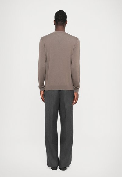 Brown knitted sweater with long sleeves, ribbed neckline, and cuffs, paired with gray pleated trousers, featuring a relaxed fit and straight leg.