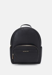 Mochila de cuero negro con forma redondeada, superficie texturizada, un bolsillo frontal con cremallera y un asa en la parte superior. Presenta un logo de marca dorado.