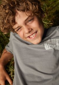 Pelēks kokvilnas t-krekls ar baltu uzrakstu "Blue Ridge". Audums izskatās mīksts, ar brīvu piegriezumu un apaļu kakla izgriezumu.