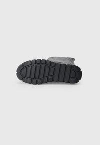 Black rubber boot sole with a textured, patterned design. Features deep grooves for traction and a slightly raised heel.