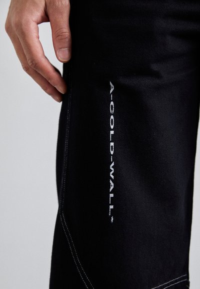 Sorte denimbukser med hvid syning og logoet "A-COLD-WALL*" på siden. Stoffet har et tekstureret udseende og en slim fit.