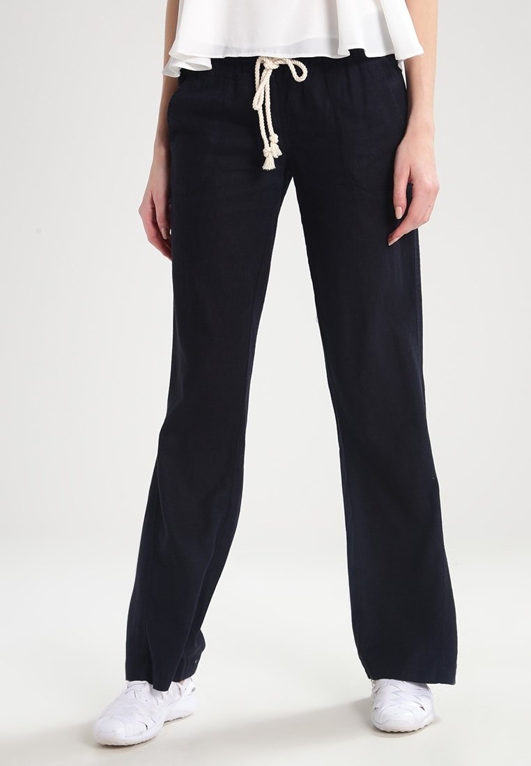 Navy linen blend pants with a relaxed fit, featuring a drawstring waist and side pockets, paired with white sneakers.