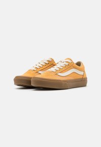 Zapatillas de gamuza en amarillo mostaza con cordones y acentos en crema. Diseño de caña baja con punta redondeada y suela de goma.