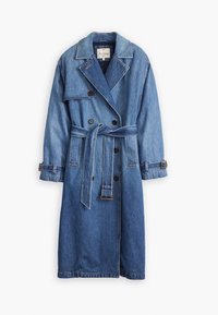 Long trench en denim avec boutons croisés, taille ceinturée, larges revers et poignets ajustables sur fond blanc.