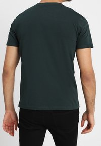 Mörkgrön kortärmad t-shirt med rund halsringning, gjord av mjukt bomullstyg, med en enkel design och rak nederkant.