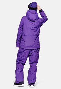 Lila isolierte Skijacke und -hose, ausgestattet mit Kapuze, elastischen Manschetten und verstellbarem Saum. Das Material wirkt glatt mit matter Oberfläche.