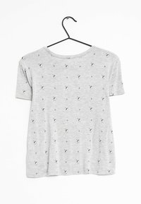 Camiseta gris de manga corta hecha de algodón suave, con un estampado repetido de pequeños pájaros y motivos florales en toda la tela.