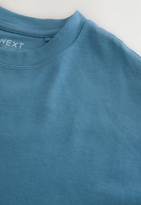 Vaaleansininen puuvillainen crew-neck -t-paita, jossa on ribsireuna, sileä rakenne ja yksinkertainen muotoilu. Kauluksessa on tuotemerkki.
