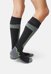 Black and gray socks with green accents, featuring a ribbed top and contrasting heel and toe, designed for comfort and durability.