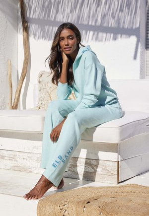 Light blue hoodie and matching joggers feature soft fabric and relaxed fit. The joggers have "ELB SAND" printed on the side.