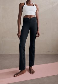 Czarne legginsy fitness o tapered kroju i elastycznym pasie, w połączeniu z białą crop top. Gładki, elastyczny materiał.