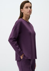 Felpa viola con maniche lunghe, scollatura rotonda, tasche laterali e una vestibilità comoda realizzata in tessuto morbido. Design casual con polsini a coste.