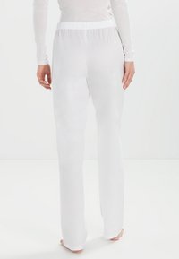 Witte, lichte broek met een relaxte pasvorm, voorzien van een elastische tailleband en een soepele textuur, ontworpen voor comfort en bewegingsgemak.