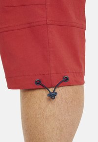 Rote Shorts mit glatter Textur, ausgestattet mit einem Kordelzugverschluss und verstärkten Nähten am Saum. Verfügt über ein einzelnes Seitentaschen-Detail.