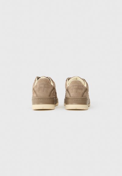 Pruunist nahast sneakersid madala profiiliga ja kreemjas kummist tallaga. Omab perforatsioonidega disaini kandadel ja minimalistlikku kaubamärgi esitlemist.