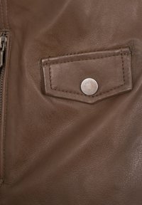 Braunes Lederetui mit einem silbernen Druckknopf, ausgestattet mit einer strukturierten Oberfläche und genähten Kanten, platziert auf einem Ledergarne.