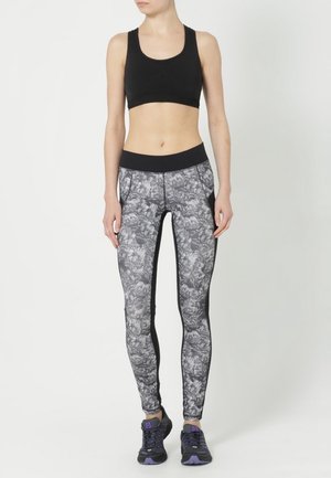 Reggiseno sportivo nero abbinato a leggings a vita alta grigi e neri con un design elegante e pannelli laterali neri.
