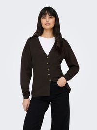 Brauner Cardigan mit tiefem V-Ausschnitt, langen Ärmeln und sechs Knöpfen vorne. Hergestellt aus weichem Material, kombiniert mit hoch taillierten schwarzen Hosen.