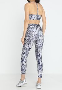 Sport bra and leggings set in a gray and navy abstract pattern. The fabric is smooth with a high waistband and a strappy back design.