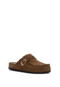 Zoccolo in suede marrone, con fibbia in argento sul lato e suola in gomma nera, angolato a destra su uno sfondo bianco.