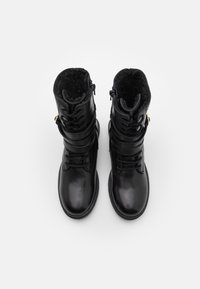 Pár černých kožených šněrovacích bot se zipy po stranách a kožešinovou podšívkou, pohled shora na bílém pozadí.