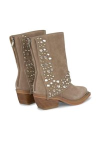 Botines de ante beige con rhinestones decorativos en el lado exterior, puntera redondeada y tacón de madera apilado. Cremalleras en el lateral para el cierre.