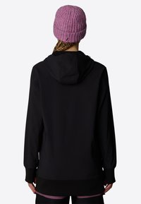 Svart hoodie med en avslappnad passform och matchande ribbade ärmar. Baksidan har en huva, och en rosa stickad mössa bärs på huvudet.