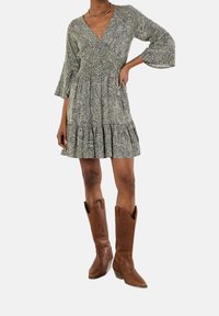 Short-sleeved, patterned dress with a V-neck, gathered waist, and flared skirt. Paired with brown cowboy boots featuring decorative stitching.