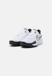 Une paire de baskets Nike Air Zoom blanches et noires avec un tissu en maille, un design à lacets et un logo swoosh noir sur le côté, présentée sur fond blanc.