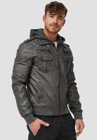 Chaqueta de cuero gris con capucha, puños acanalados y bolsillos. Presenta un cierre frontal con cremallera y un acabado texturizado. Diseño informal.