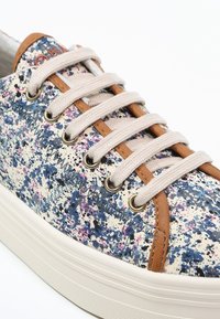 Canvas sneakers med ett flerfärgat sprutmönster i blått, rosa och vitt, med beige snörningar och bruna läderdetaljer.