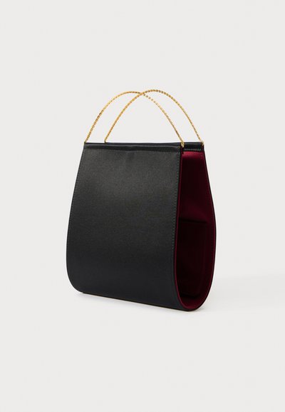Musta käsilaukku, jossa on sileä ulkopinta, kontrastoiva viininpunainen sisus ja kaksi kullanväristä ketjusankaa kantamista varten. Laukku on modernin kaarevan muotoinen.