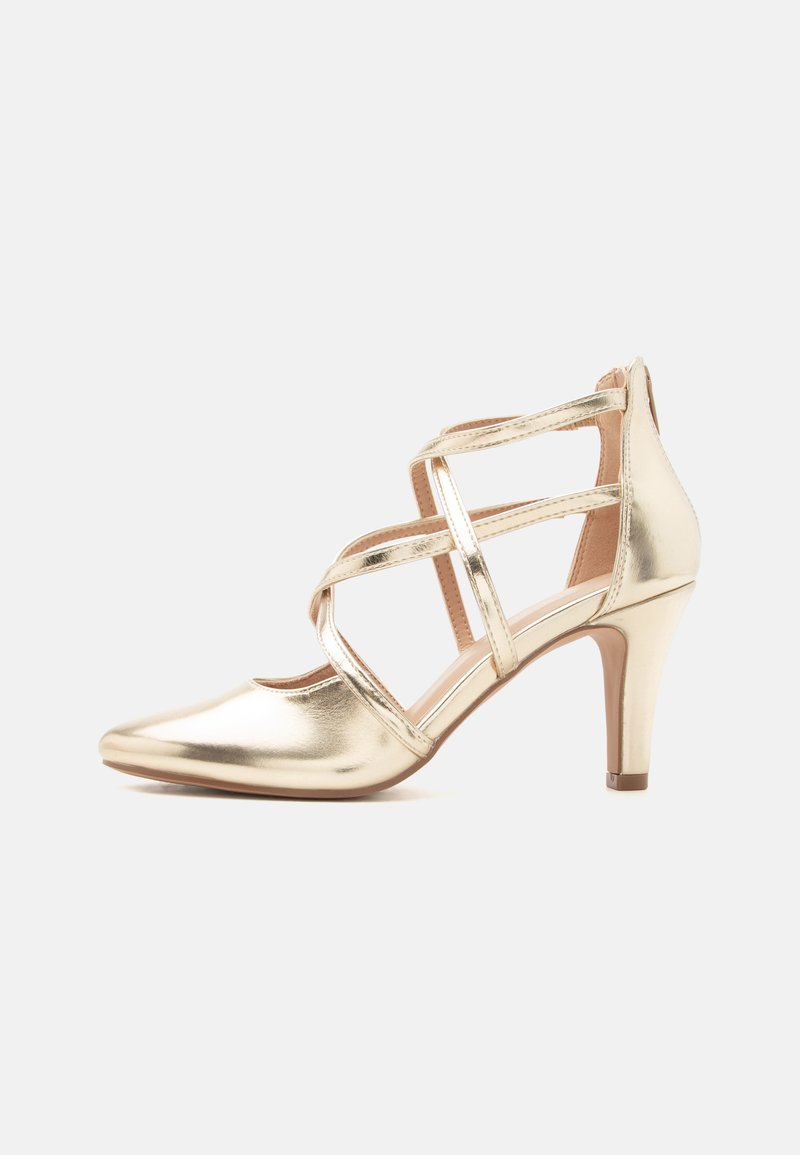 Χρυσό μεταλλικό γυναικείο παπούτσι με ψηλό τακούνι και μυτερή μύτη, με σταυροειδείς λουρίδες στον αστράγαλο και φερμουάρ στο πίσω μέρος, πάνω σε λευκό φόντο.